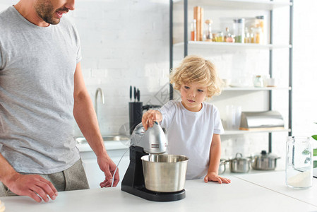 男人在厨房使用搅拌机时站在儿子身图片