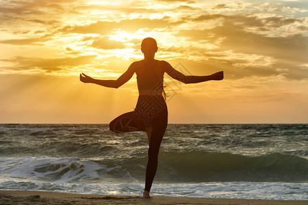 女孩在海边沙滩上练瑜伽后视背景图片