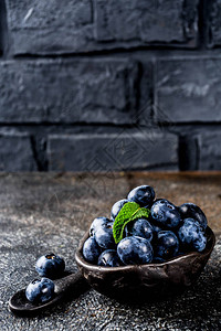 兰蔻小黑瓶小黑碗中的生鲜蓝莓深生锈背景