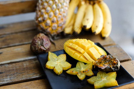 在靠近菠萝的盘子上放美味的芒果和杨桃图片