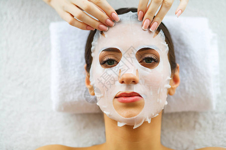 美丽美丽的女人在美容院戴着面具躺在按摩台上纯净清新的肌肤皮肤护图片