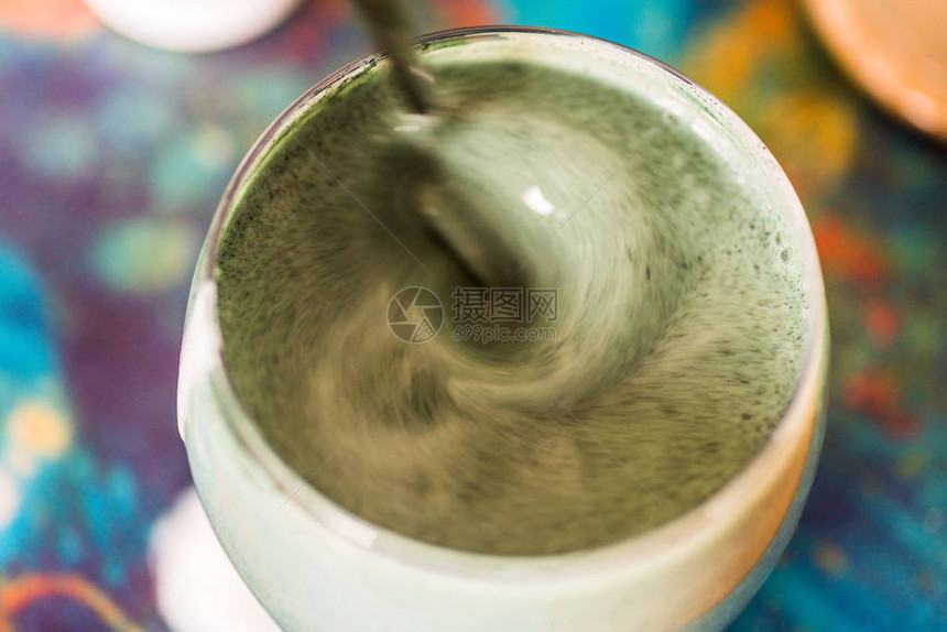 与厨房桌上绿色螺旋藻粉混合的玻璃杯中新鲜Kefirprob图片