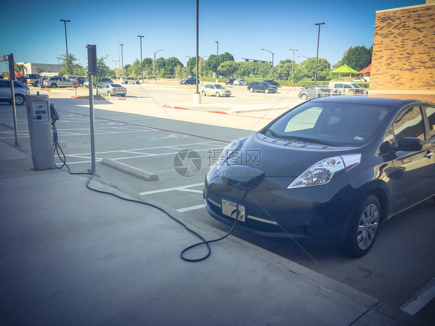 充电器插入电动汽车引擎盖的充电站可充电池车辆在美国零售店停车场加油未来汽车图片