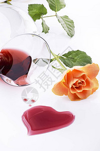 由葡萄酒所形成的心光影从一杯和一朵玫瑰中溢出图片