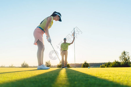 夏季与经验丰富的职业球员在高尔夫课上锻炼击球技术的漂亮身材的图片