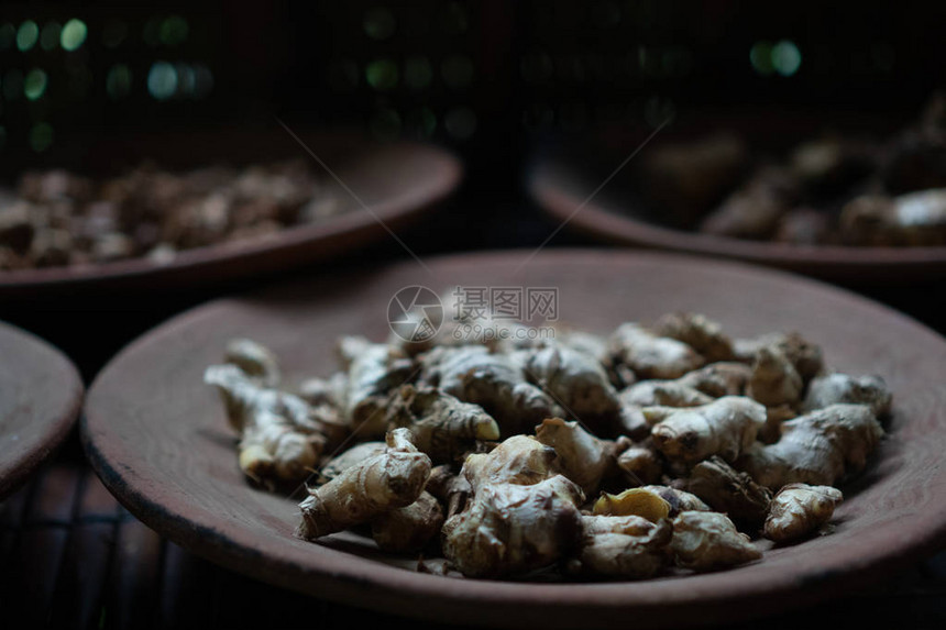 在质朴的粘土棕色盘子上特写干姜图片