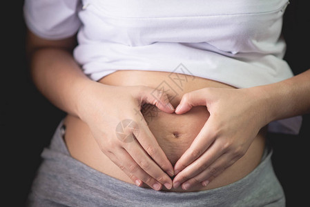 孕妇将手握在肚子肿胀的肚子上图片