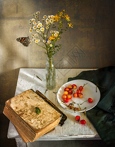 有鲜花一本书一颗樱桃和一只蝴蝶的静物画图片