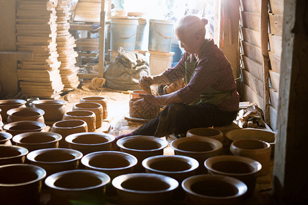 在陶轮上制作陶罐的女人图片