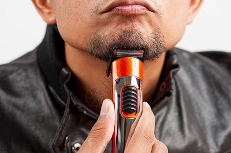 一个人用电动剪发机修胡须的男人图片