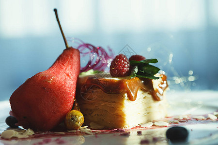 精致的餐厅甜点焦糖milfuelle与辣梨浆果酱和杏仁片放在白盘上图片