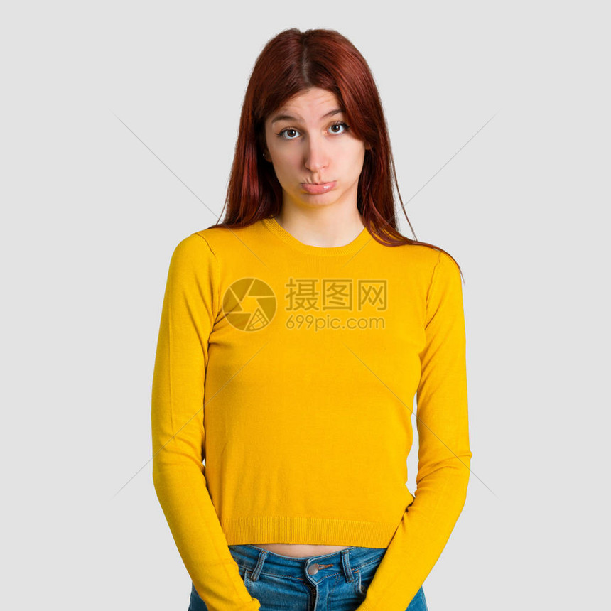穿着黄色毛衣的年轻红发女孩带着悲伤和沮丧的表情图片
