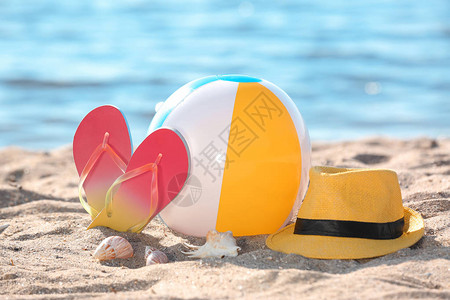 海边沙滩上的充气球帽子和人字拖海滩物体图片