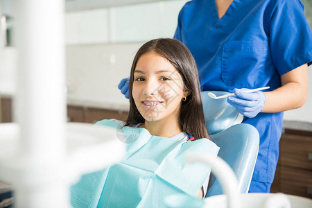 带着牙套坐在椅子上牙医站在诊所看牙医的笑图片