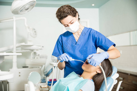 在诊所治疗少女时使用唾液喷射器和牙科钻图片