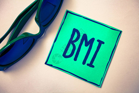 文字书写文本Bmi体重指数的商业概念确定了与身高相关的健康体重范围绿纸米色背景太阳镜理念图片