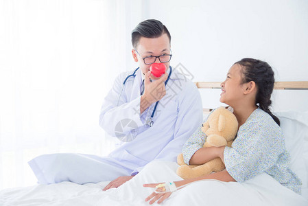 小儿科男医生在鼻子上抱着红心球与图片