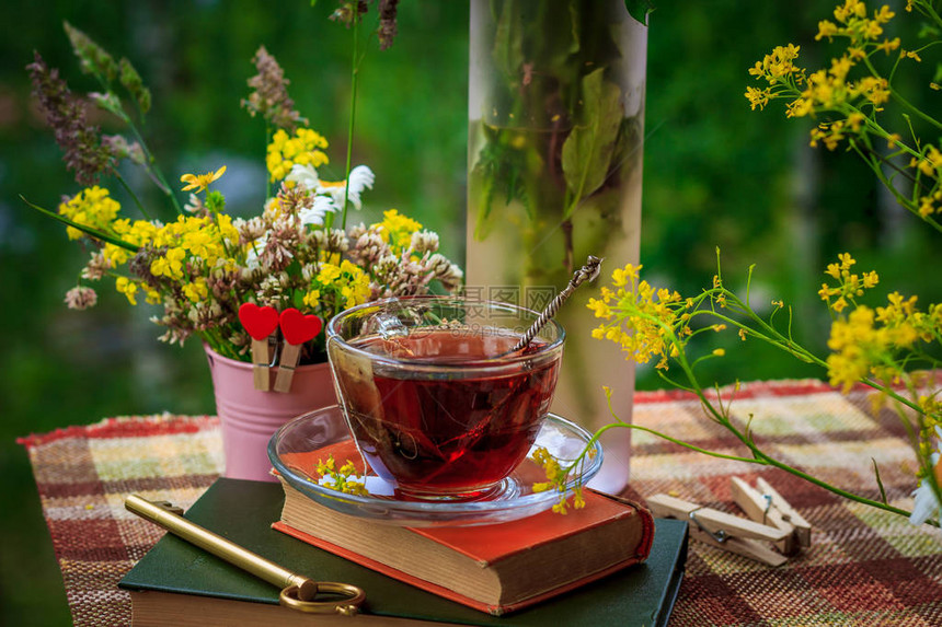 粉红色铁桶里的一杯茶和野花图片