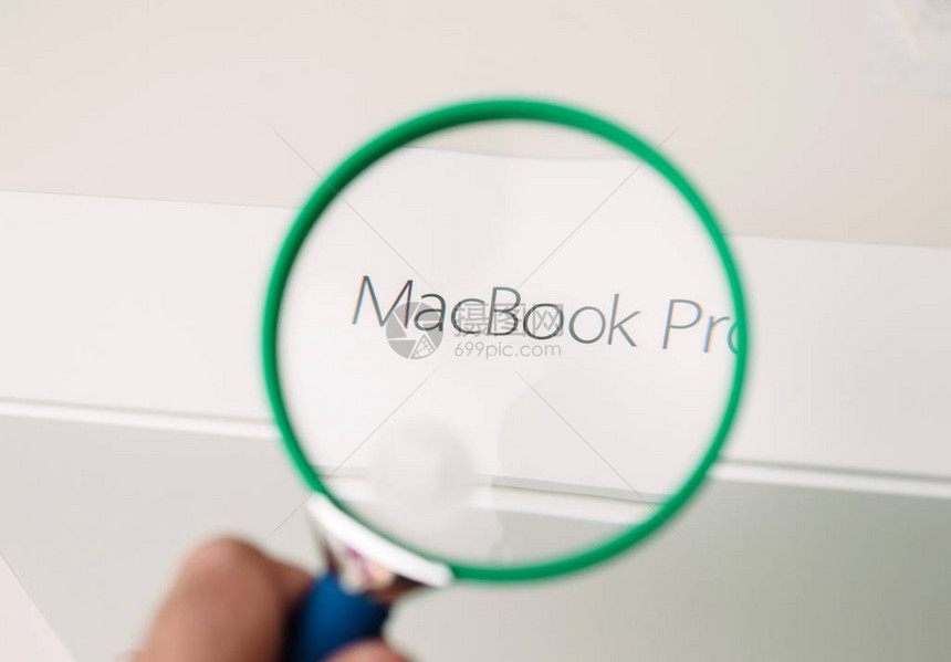 男人用放大镜看新的AppleMacBookPro笔记本电脑的盒子图片