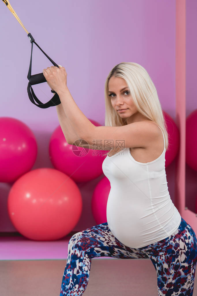 在健身房用Trx健身带对有吸引力的年轻金发孕妇进图片