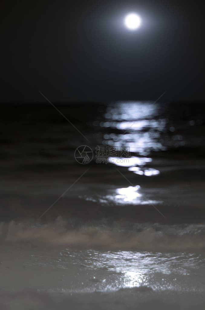 夜晚的月亮海浪上的月光沙滩上的冲图片