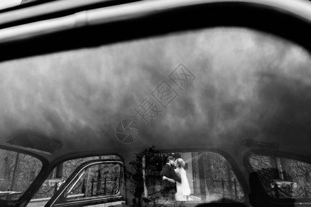 时尚的新娘和新郎在车上接吻豪华新婚夫妇在城市街道拥抱和拥抱浪漫多情的感时刻从窗户玻璃看图片