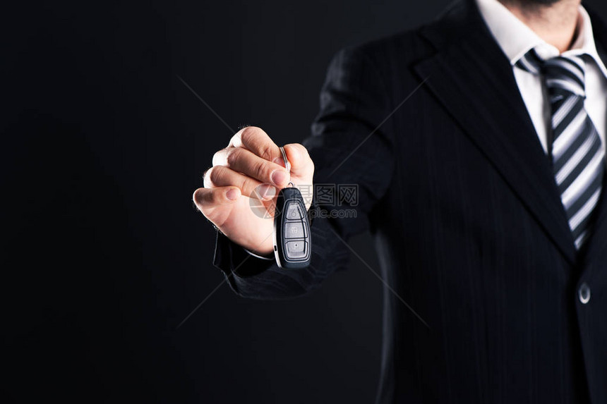 汽车销售员在黑暗背景上交出你的新车钥匙经销图片