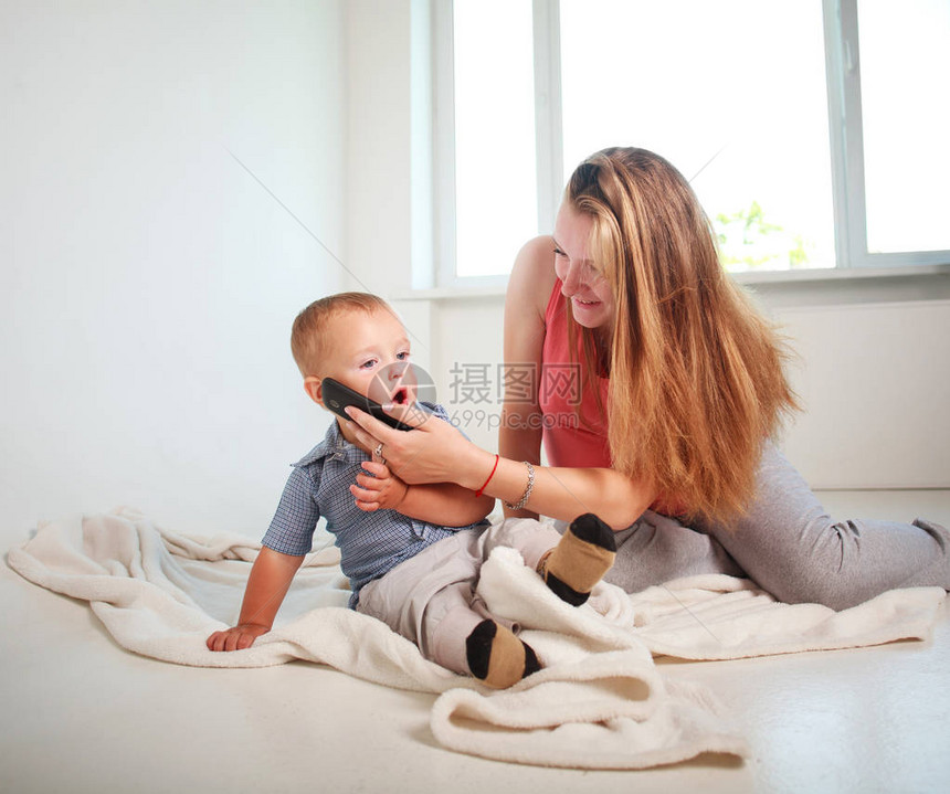 母亲和孩子小的儿女用家里的智能手机进行交流在家中图片