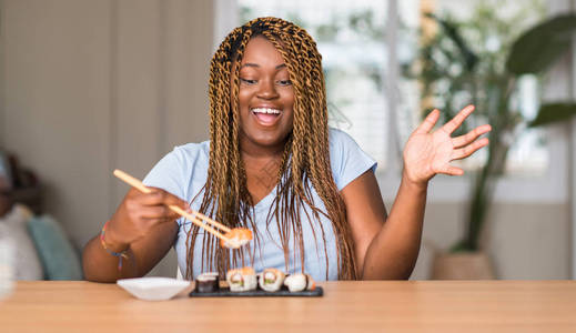 吃寿司的非洲裔美国女非常高兴和奋图片