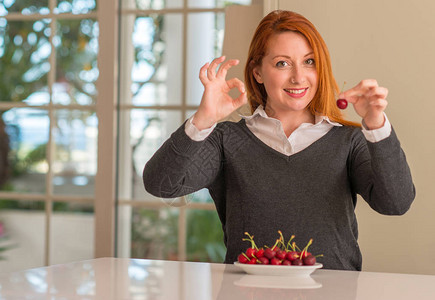 红发女人在家里吃樱桃做好用手指的标志图片