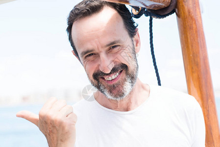 穿着帆船行驶的英俊年长男子用手和指着满图片