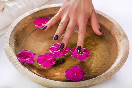 用水触摸木碗里的花修指甲和水疗美容理念选择图片