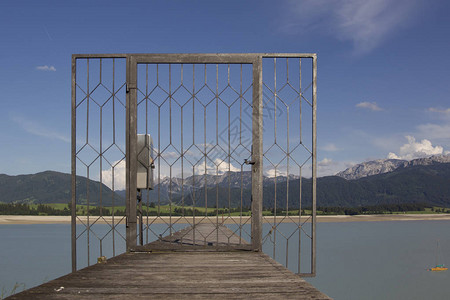 穿过一个锁着的铁丝网门向着阿尔卑斯山脉方向在干燥的福吉恩河对图片