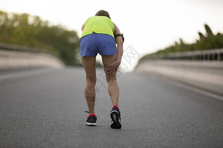 运动受伤的女运动员在市街上奔跑图片