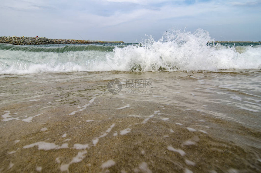 海浪在云层和蓝天空背景上撞击海滩的模糊和有选图片