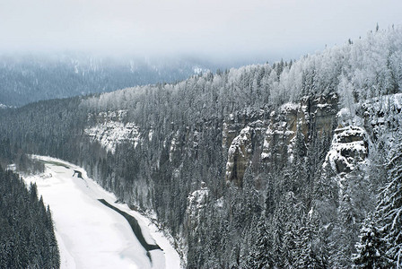 从岩石顶端到冰冻河流的风景在冬季积雪覆盖的阴暗地貌图片