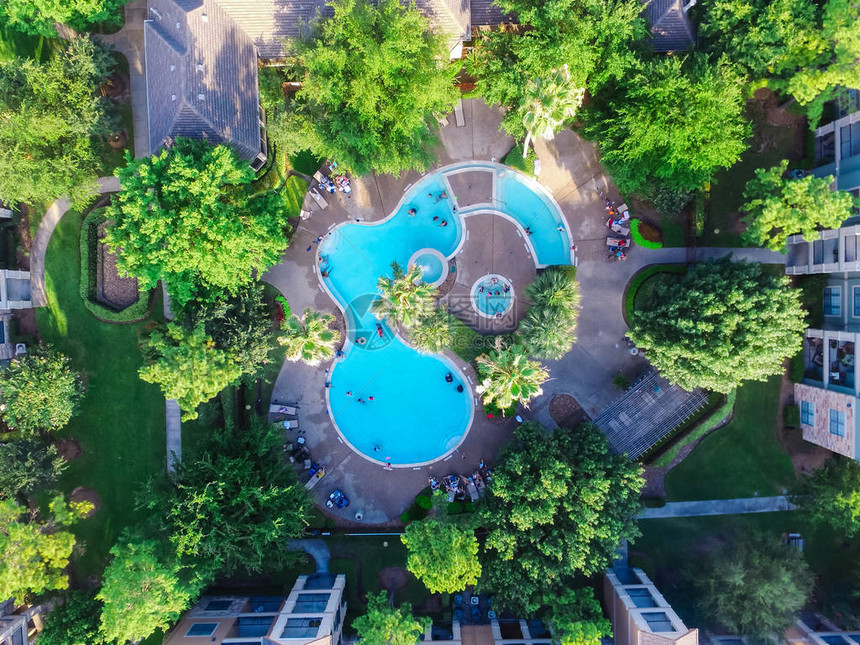 美国得克萨斯州休斯顿日落时住的典型多层公寓中的游泳池空中景象周围环绕着绿色花园折叠椅家具和身份不图片