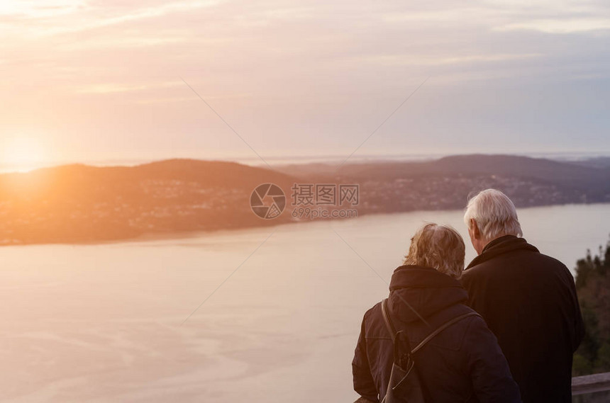 爱着佛洛伊恩山的老夫妇卑尔根挪威的浪漫日落古典音调过滤颜色风格以及模糊和亮耀斑图片