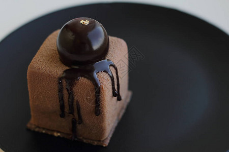 巧克力蛋糕和圆奶油片在黑色盘子上融图片