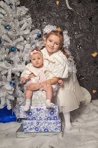 两个可爱的亲生妹带着一棵白色圣诞树一起摆图片