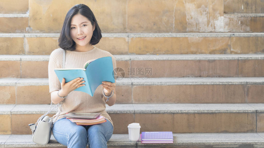 拥有教育书籍和咖啡杯的学生少女坐在楼图片