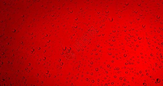 红色玻璃窗背景上的雨滴图片
