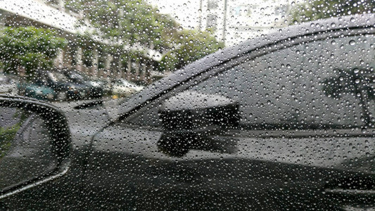 雨滴落在有汽车背景的窗户上图片