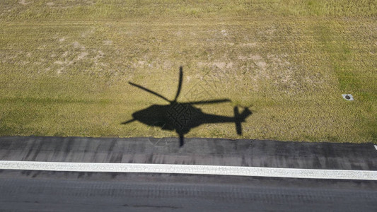 直升机飞越草地和沥青的阴影图片