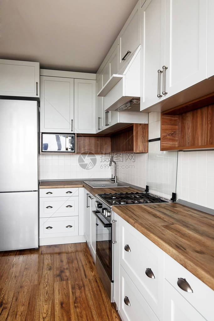 时尚的浅灰色厨房内部配有现代橱柜和不锈钢器具斯堪的纳维亚风格的厨房设计硬木地板和木制台面花岗岩水槽图片