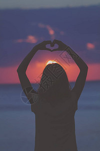 在沙滩上用手做心形的女孩背景图片