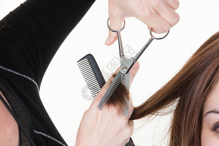 特写微距拍摄图像发型师美发师用剪刀和梳子在沙龙剪掉顾图片