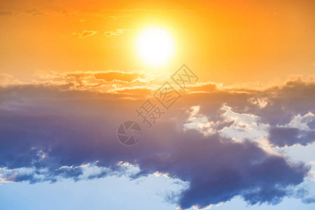 橙色天空中的日落大太阳和蓝云图片