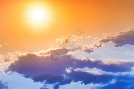 橙色天空中的日落大太阳和蓝云图片