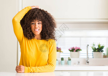 在厨房穿着黄色毛衣的非洲裔美国女人对问题感到困惑和疑惑图片